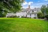 Expansive front yard with a stone retaining wall, mature trees, and well manicured landscaping including established shrubs