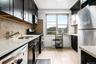 Kitchen with stainless steel appliances, dark cabinetry, light stone countertops, and tasteful backsplash