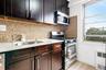 Kitchen featuring stainless steel appliances, decorative backsplash, radiator heating unit, and light stone counters