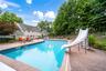In-ground swimming pool with a slide, surrounded by a concrete pool deck, and a detached gazebo
