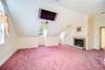 Sloped ceiling room featuring a brick fireplace with stone hearth, multiple windows for sun/moonlight