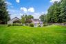 Expansive lawn area featuring a fenced swimming pool, adjacent gazebo, and a secondary garage structure with covered entry