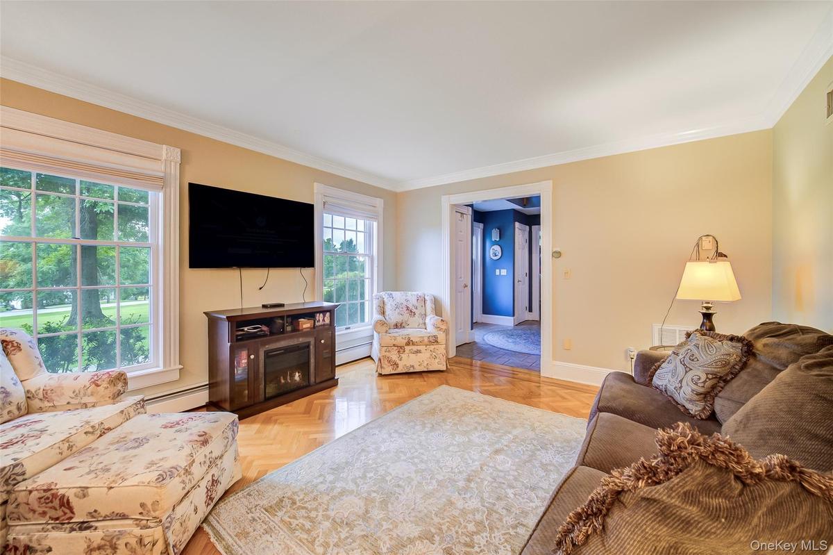 Spacious living room featuring hardwood flooring, large multi-pane windows with natural light, and warm yellow-toned walls throughout the room