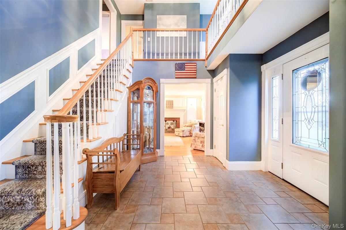 Two-story foyer featuring tile flooring and a grand staircase with wood-finish handrails and custom molding