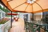 Expansive outdoor deck featuring a white baluster railing, and a covered dining area