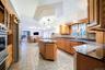 Expansive kitchen featuring wood cabinetry, granite countertops, a center island with ample storage, stainless steel appliances, and tile flooring