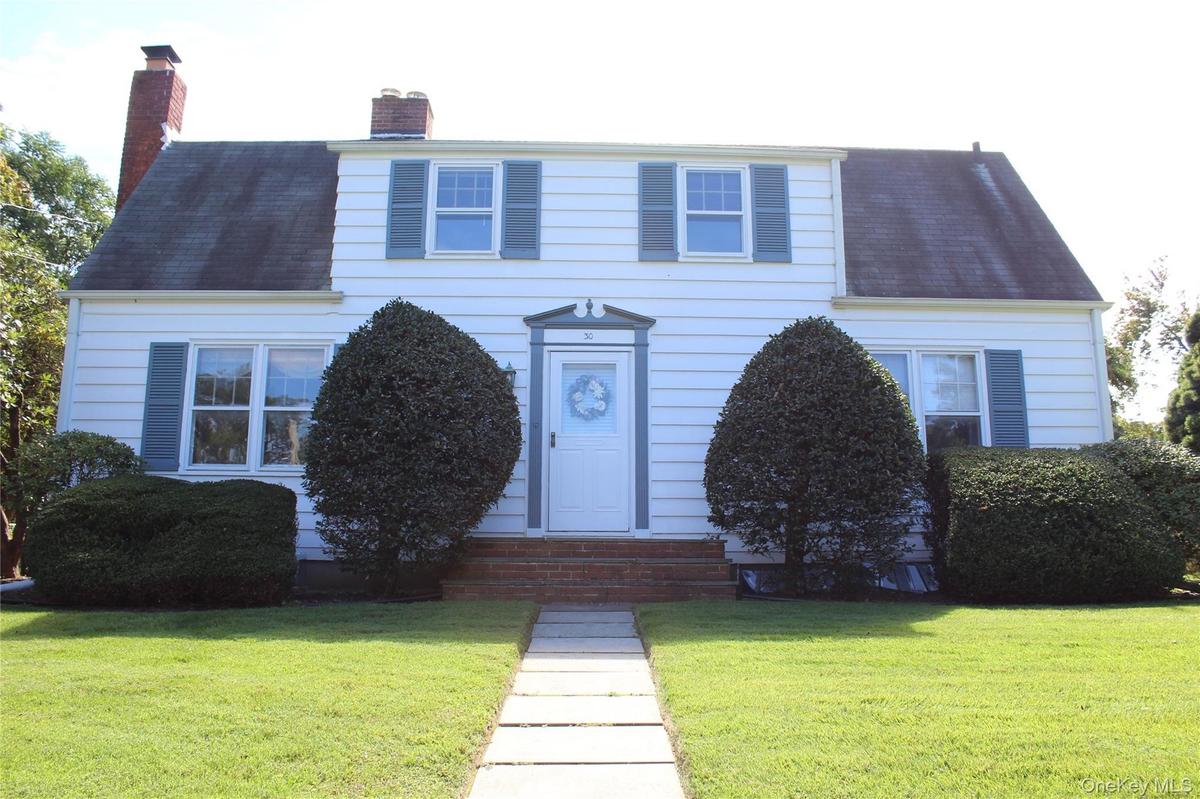 White siding exterior with a gambrel roof and two prominent brick chimneys