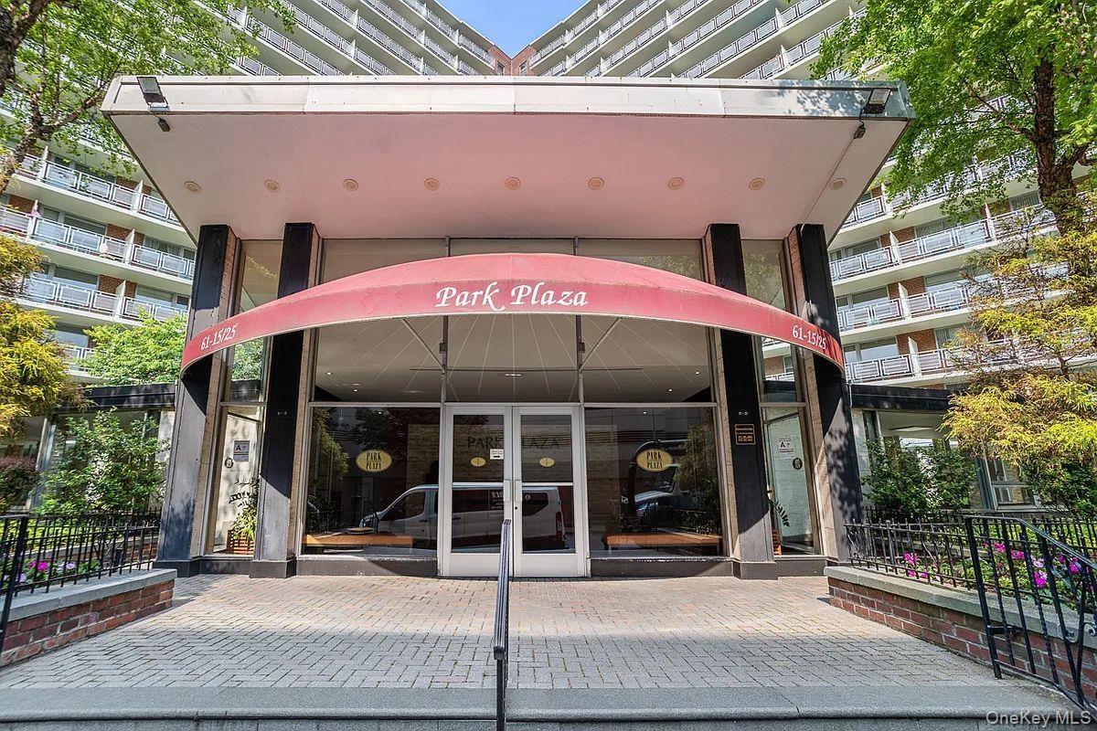 Building entrance featuring a red awning, full-height glass doors, and a paver walkway
