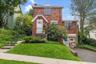 Brick colonial, perched on a hill with driveway.