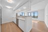 Open-concept kitchen with white cabinetry, stainless steel appliances, light-toned countertops, and wood-finish flooring
