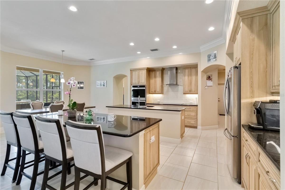 Large kitchen with double ovens, stainless steel appliances, granite counters and two islands. One island serves as an eating bar. The other island is