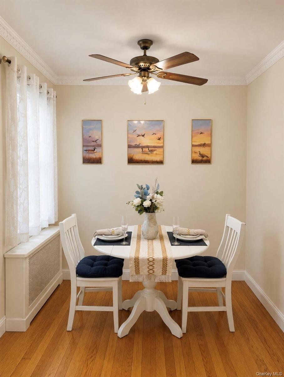 Dining area featuring wood-finish flooring, crown molding, and a ceiling fan with integrated lighting
