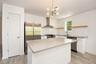Kitchen with white shaker cabinetry, center island with seating overhang, stainless steel appliances, wall-mounted range hood, subway tile backsplash 