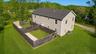 Elevated view of the home and fully fenced backyard area, bordered by lawn and mature trees.