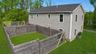 Aerial view of the rear of the home showing the two-story layout, wood-fenced backyard enclosure and open lawn.