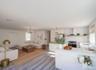 Virtually staged. Wide view of the open living space and kitchen with island and range hood.