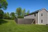Side elevation with the fenced yard area and open lawn.
