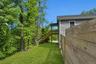 Side yard along the wood privacy fence with mature trees and the home beyond.