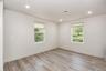 Bedroom with two windows, recessed lighting and wood-look plank flooring.
