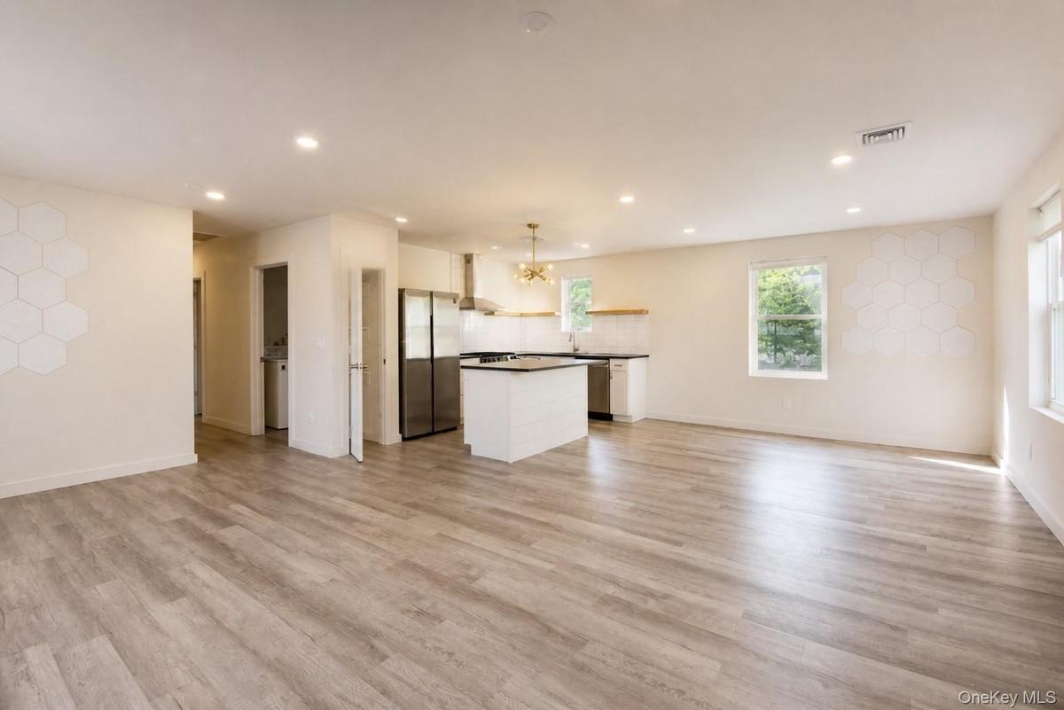 Open-concept main living area flowing into the kitchen, with recessed lighting and wood-look plank flooring.
