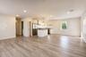 Open-concept main living area flowing into the kitchen, with recessed lighting and wood-look plank flooring.