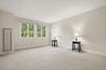 Light-toned wall finishes, expansive window, crown molding, and neutral carpeting