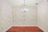 Wood-finish flooring, crown molding, and a crystal chandelier
