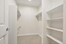 Walk-in closet featuring carpet flooring, built-in shelving, and hanging rods