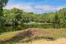 Expansive natural pond surrounded by abundant mature trees and natural vegetation