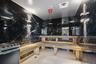 Black marble-style wall finishes, light wood benches, white hexagonal floor tiling, and a built-in heating unit