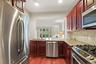 Kitchen featuring stainless steel appliances, wood-finish flooring, cherry-stained cabinetry, light-toned countertop, and tiled backsplash
