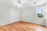 Wood-finish flooring, white walls, and a ceiling fan with integrated lighting