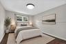 Lower level bedroom--Wood-finish flooring, white trim details, window with natural light, modern flush-mount ceiling light, and light-toned walls