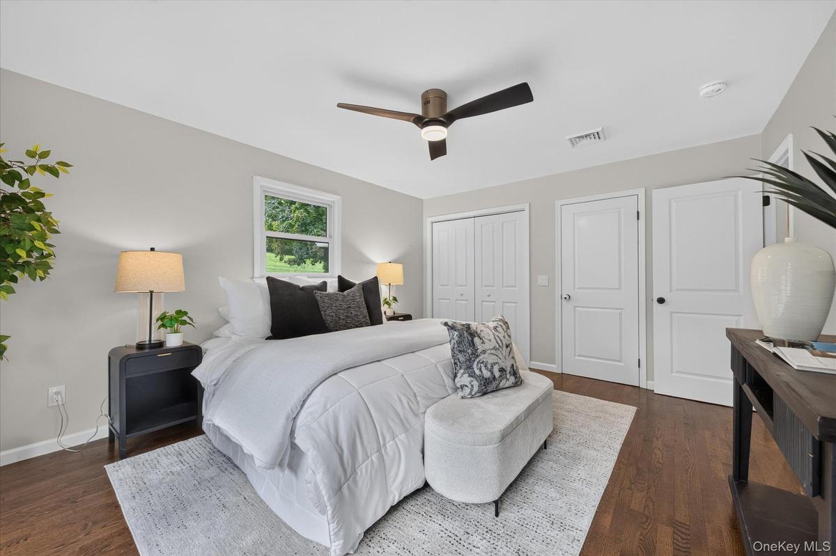 Hardwood-style flooring, white walls, two white panel doors, and a ceiling fan with light fixture