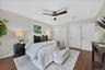 Hardwood-style flooring, white walls, two white panel doors, and a ceiling fan with light fixture