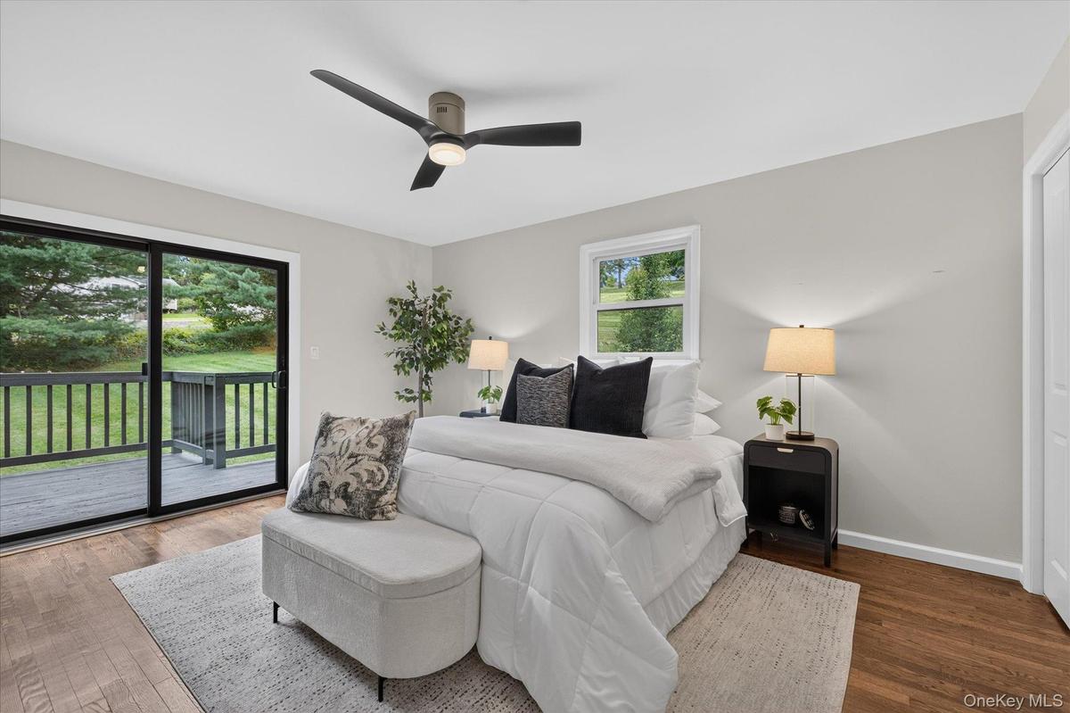 With private deck, Hardwood flooring, light gray walls, sliding glass door to exterior deck, ceiling fan with integrated lighting, and a single window