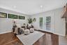 Hardwood flooring with a geometric pattern, white double doors with glass panes, recessed lighting, and a stone-faced fireplace with a wood mantle