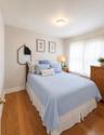 Bedroom featuring wood-finish flooring, a flush-mount ceiling light fixture, and a window with sheer curtains