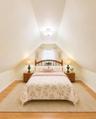Attic bedroom featuring pitched ceilings, wood-finish flooring, and a window with sheer curtains