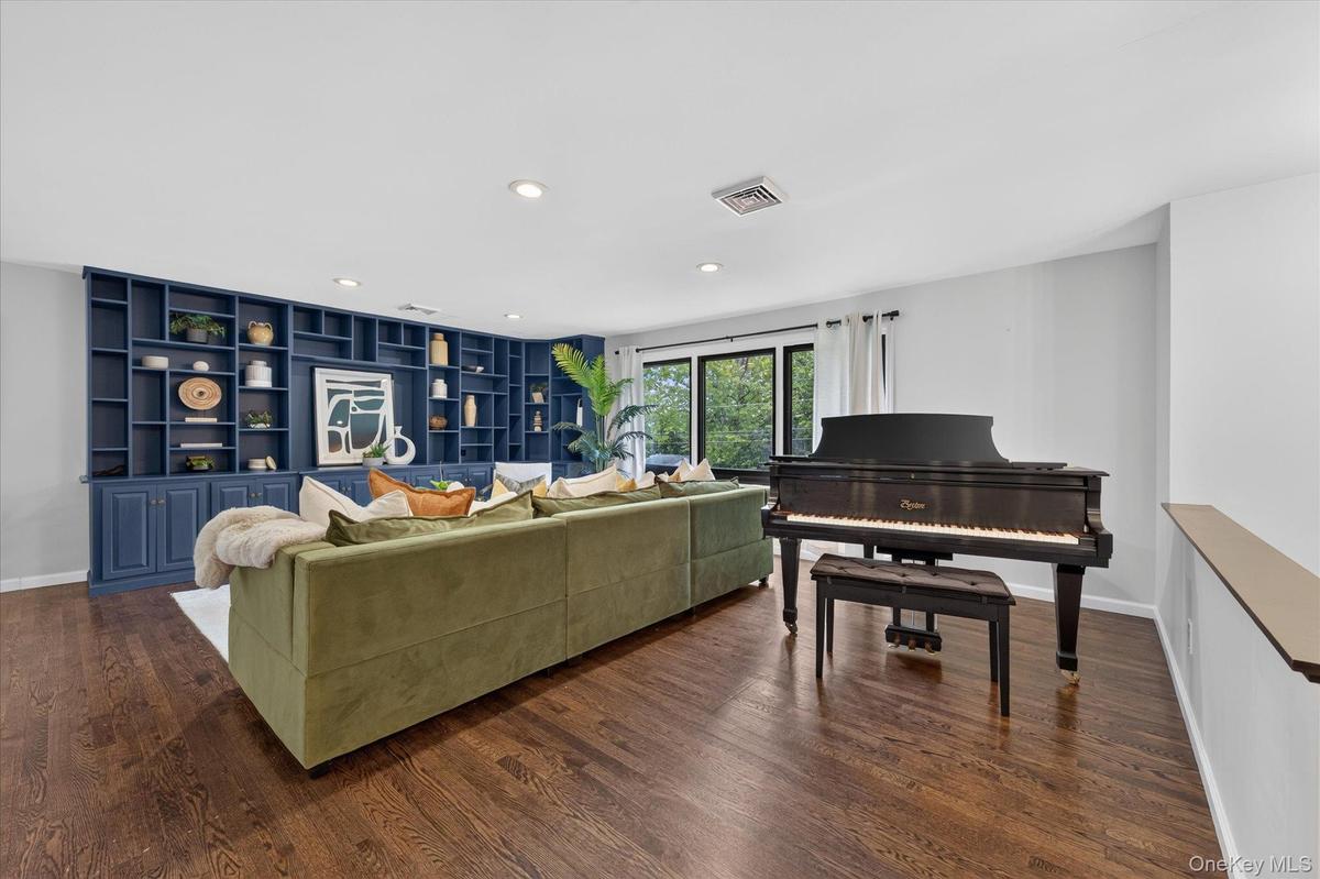 Hardwood flooring, custom built-in shelving, recessed lighting, and large windows with dark trim