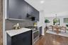 Matte navy cabinetry, white countertops with veining, stainless steel range, gray mosaic tile backsplash, and wood-finish flooring