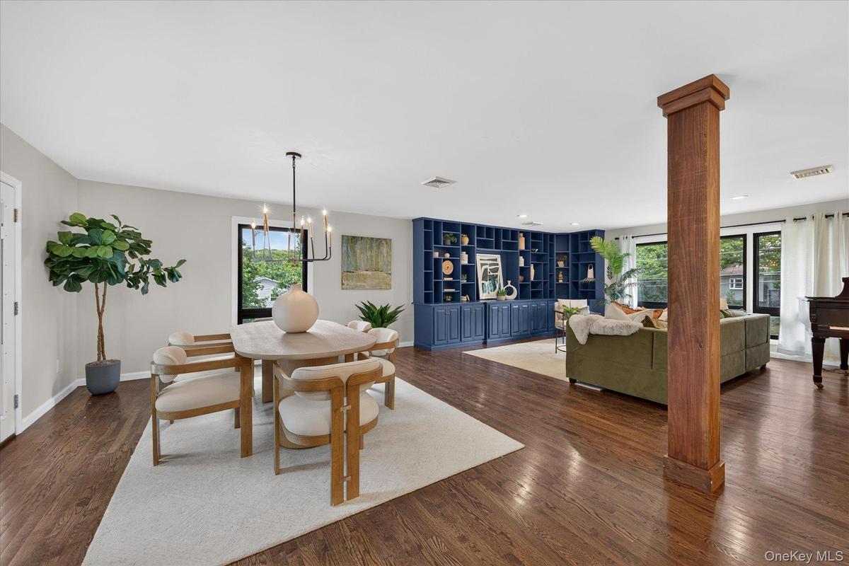 Loft-like, Open Floor plan--Hardwood flooring throughout, built-in shelving, large windows with exterior foliage, and a rectangular chandelier