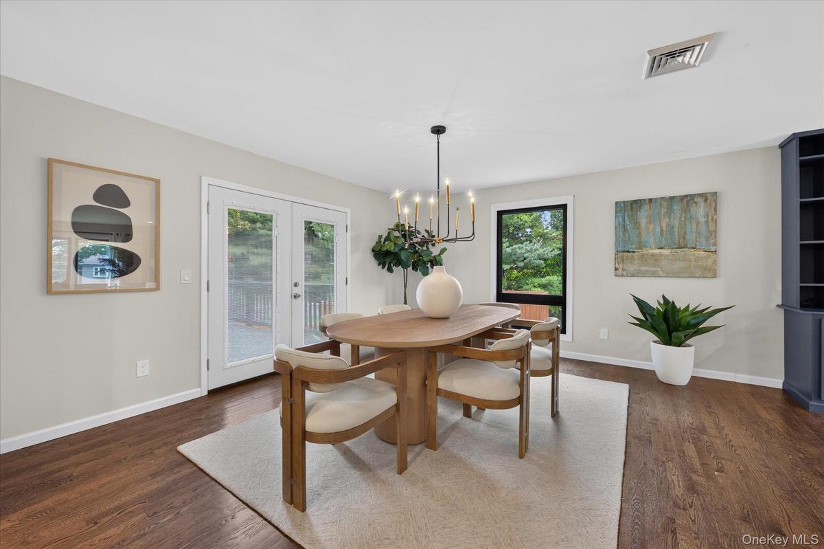 Hardwood flooring, French doors with exterior access, integrated shelving unit, and a black-framed window