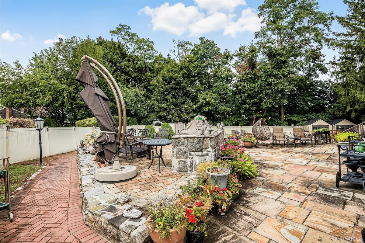 Expansive patio featuring flagstone paving, a stone-faced retaining wall, and a brick pathway