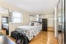 Hardwood flooring, mirrored closet doors, a built-in mirrored headboard, and a window with blinds