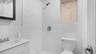 Bathroom featuring vanity, toilet, and a tile shower