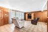 Tiled flooring, wood paneling, built-in media cabinetry, and a pass-through opening