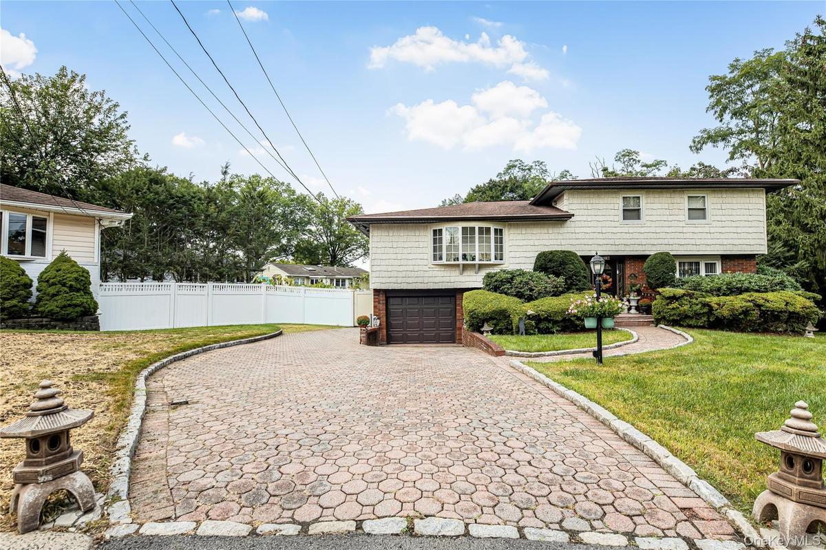Split-level residence featuring a bay window, attached garage, and a paver driveway