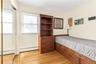 Bright interior with light wood-finish flooring, a window offering natural illumination, and mirrored closet doors