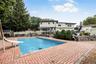 Swimming pool with a water slide, surrounded by a brick paver patio and privacy fencing